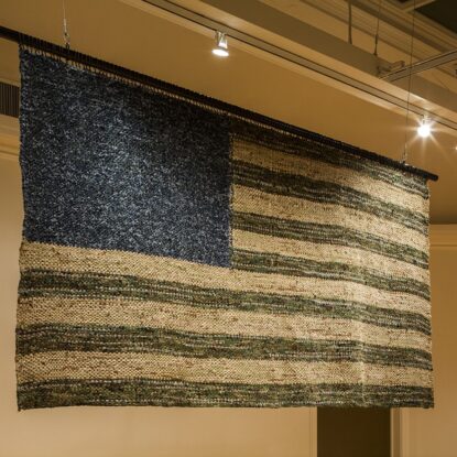 A blue, green and khaki American flag woven from the uniforms of military service members.