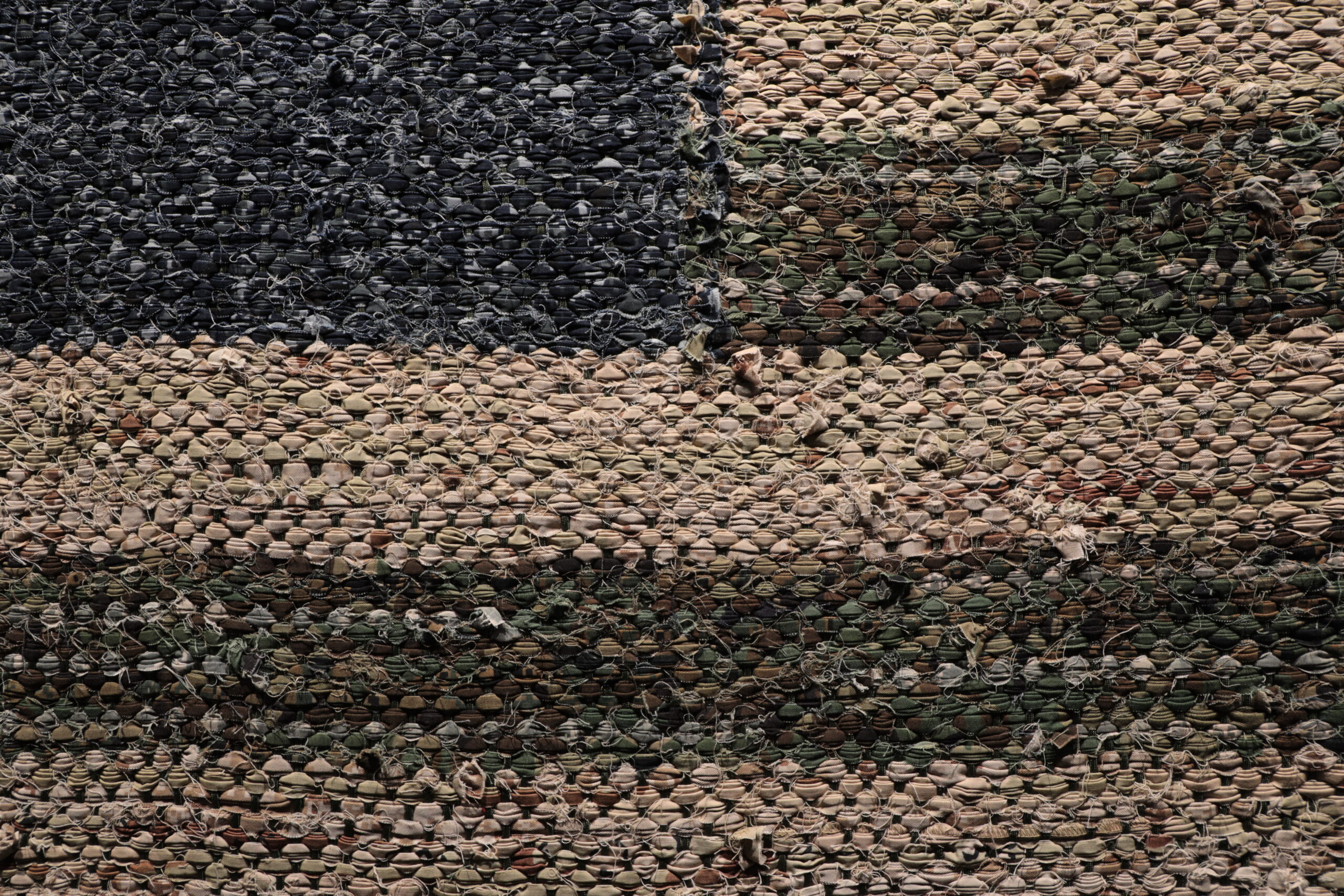 Close up view of a blue, green and khaki material from the uniforms of military service members woven into an American flag.