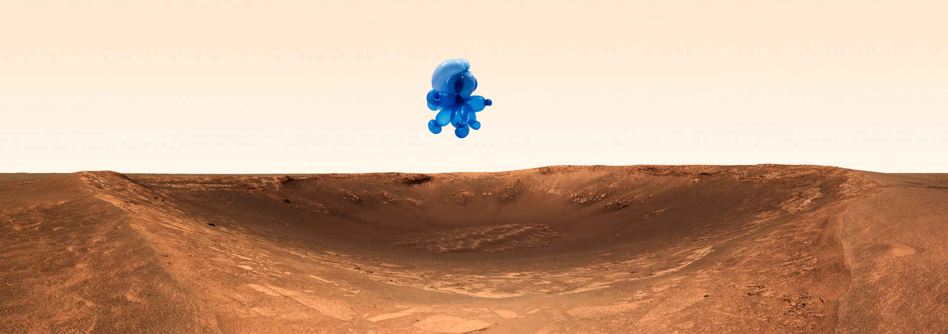 An art print depicting a blue balloon animal-like object hovering in a light orange sky above a desert crater.