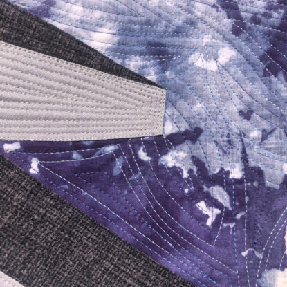 An art quilt depicting the view from an airplane window over a wing looking down at water.
