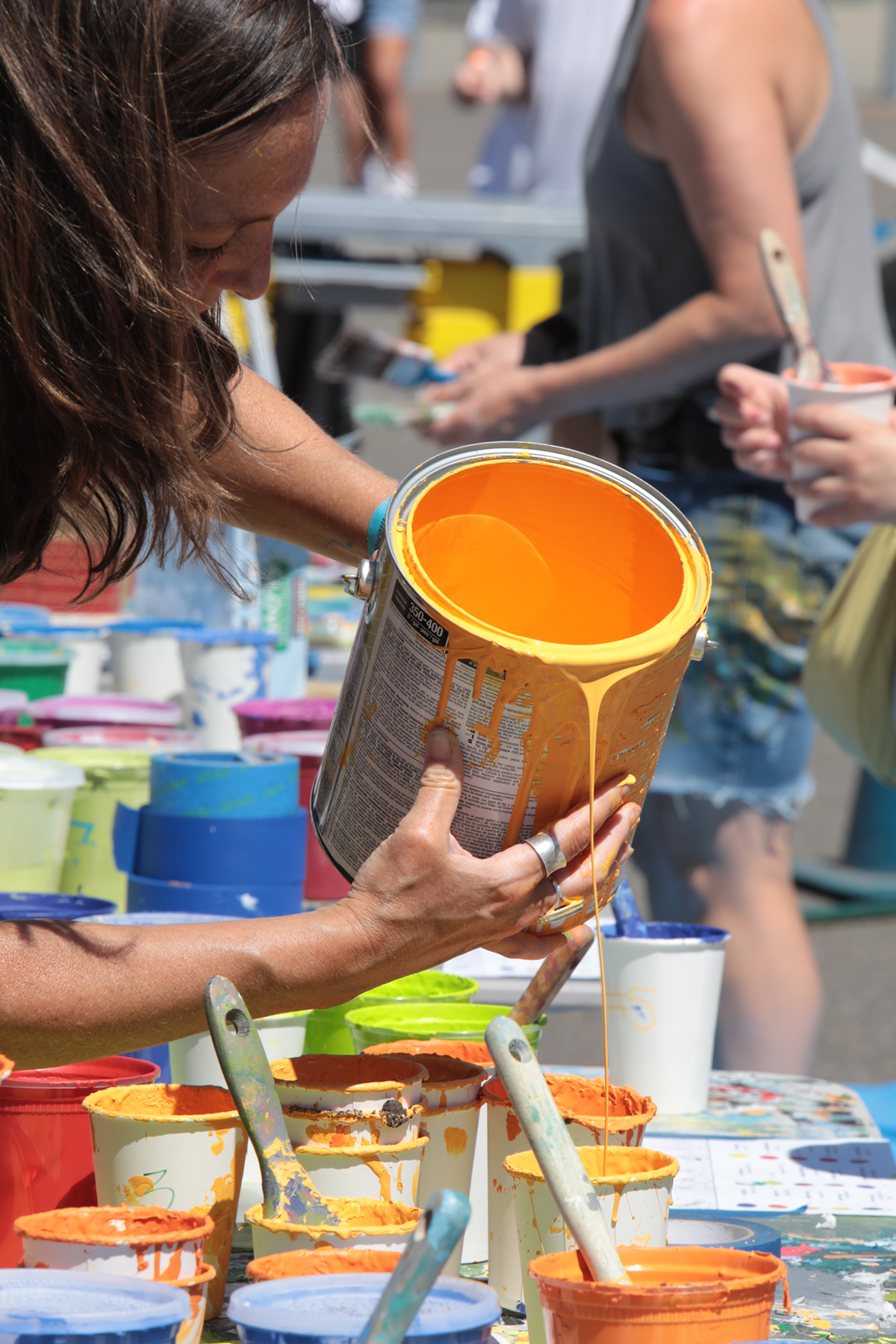 Bright orange paint is poured into cups for visitors to use.